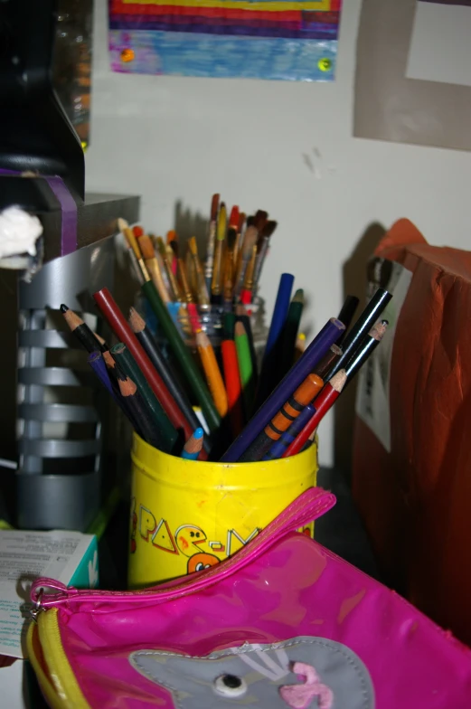 there are some different colored pens in the yellow bucket