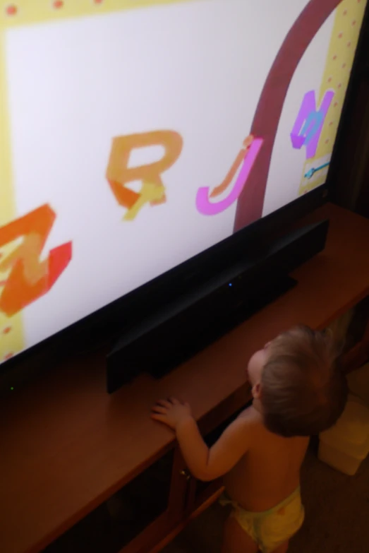 a young child with his hand on the entertainment center's television