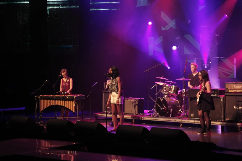 a group of women standing on top of a stage with instruments