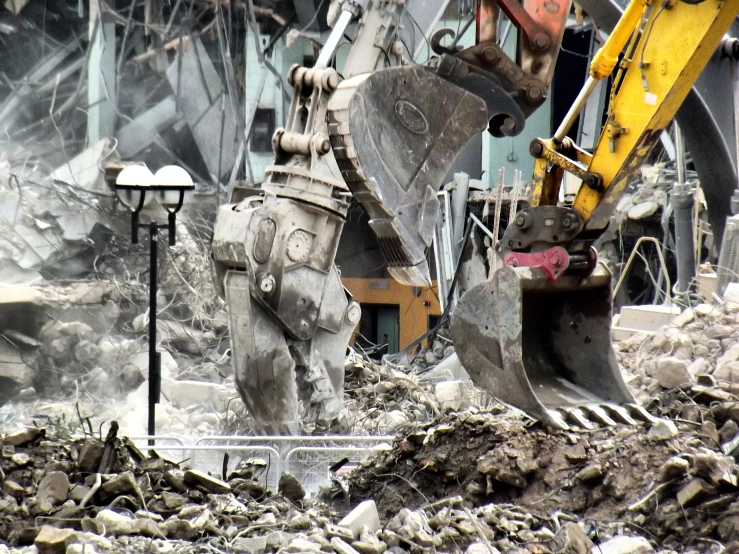 some machines digging rubble with one of them holding a shovel