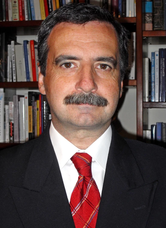 a man with a tie that is standing by bookshelves