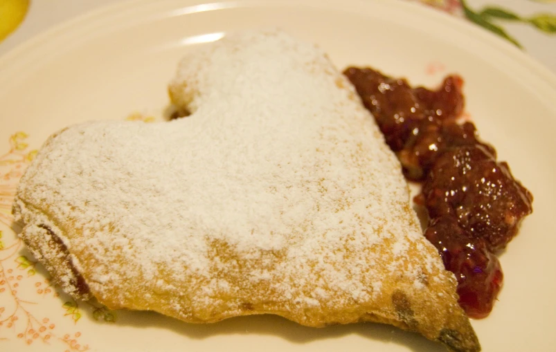 a small powdered pastry and jelly in the shape of a heart