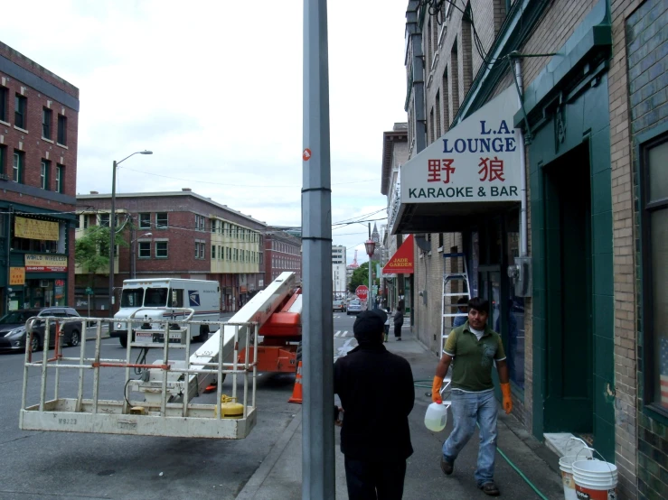 people are walking down a street while cars and buildings are behind them