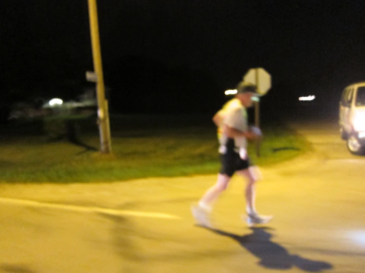 man carrying a paper bag walks across a road