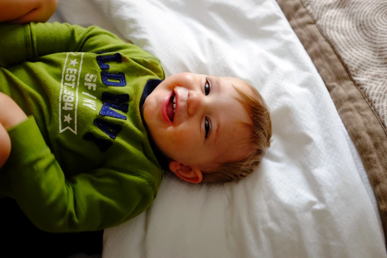 a baby laying on top of a bed smiling