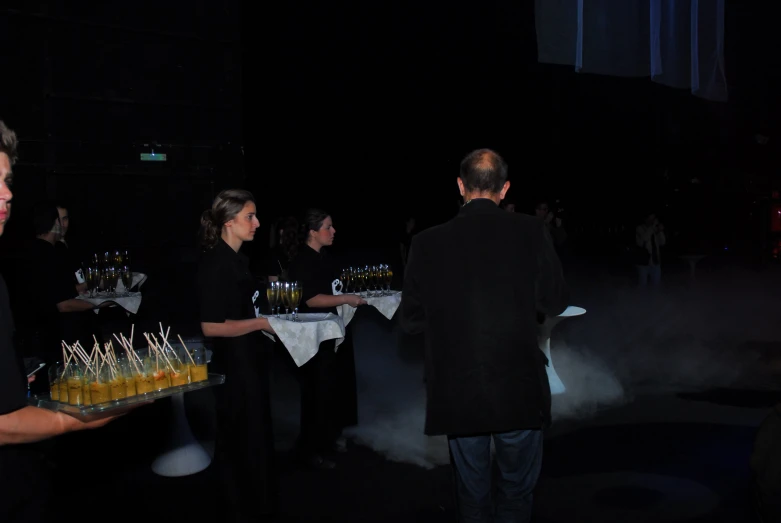 two women are serving desserts on a tray in the dark