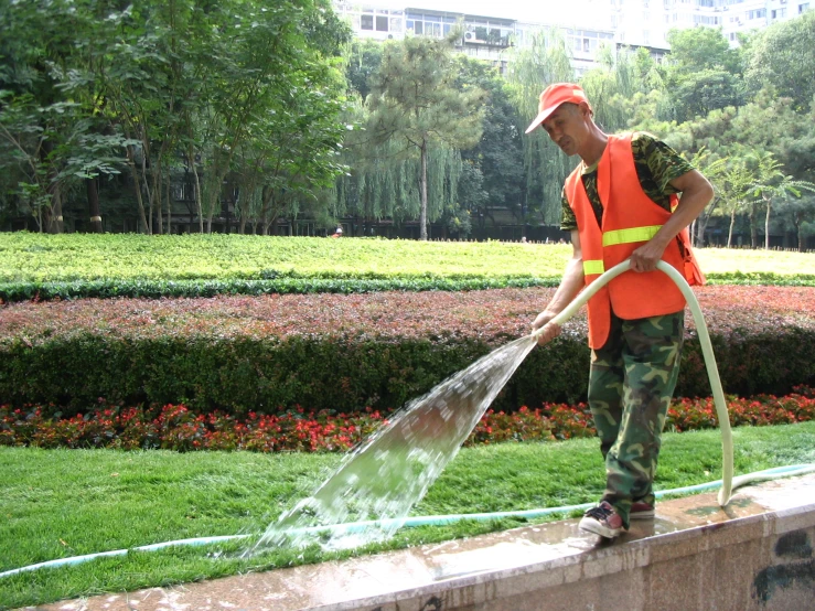 a man in a uniform is cleaning the grass with a water hose