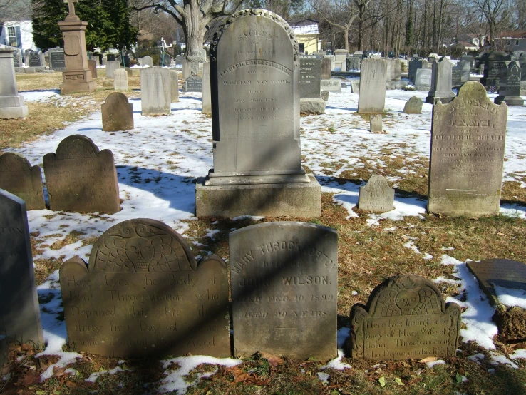 several headstones in the snowy cemetery on a bright day