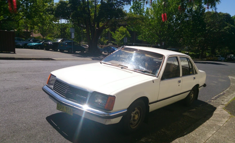 an old white car parked on the side of a street