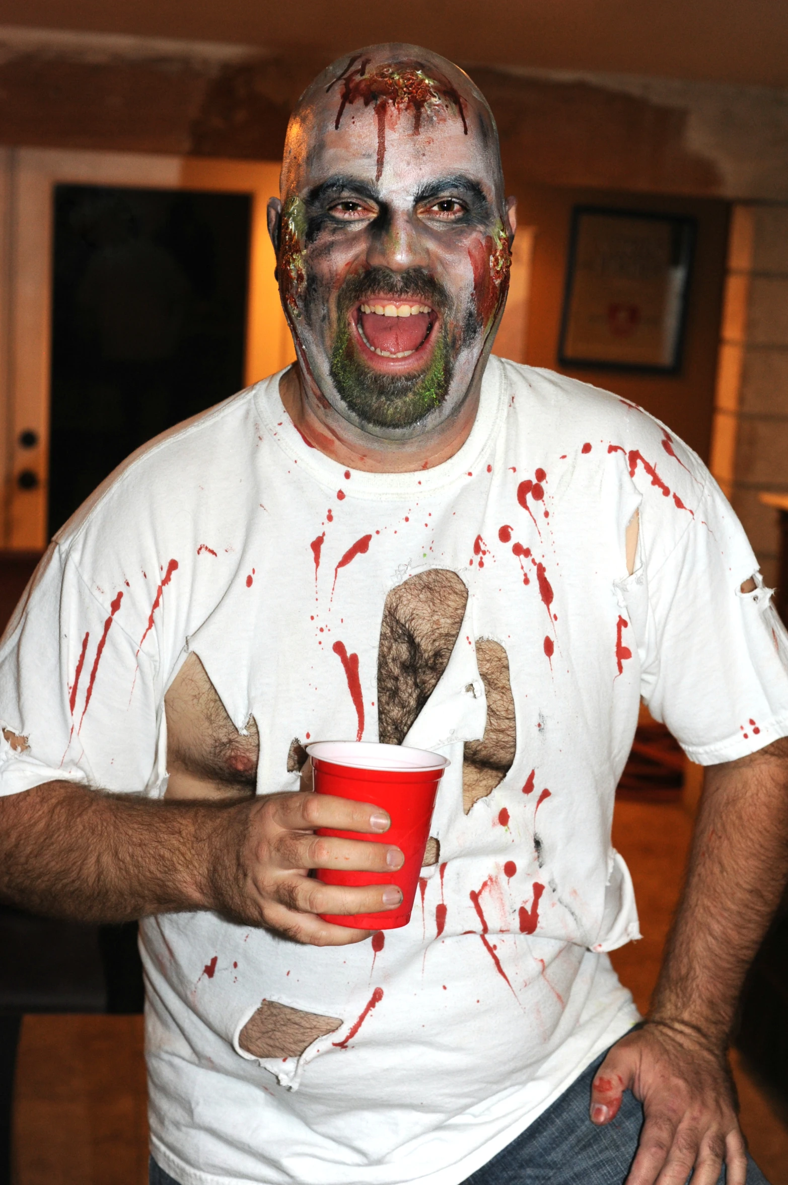 a person with colored paint on his face and face painted in white holding a cup