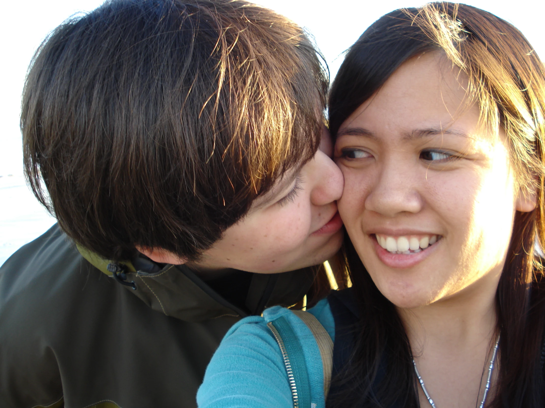 a young couple are kissing each other on the beach