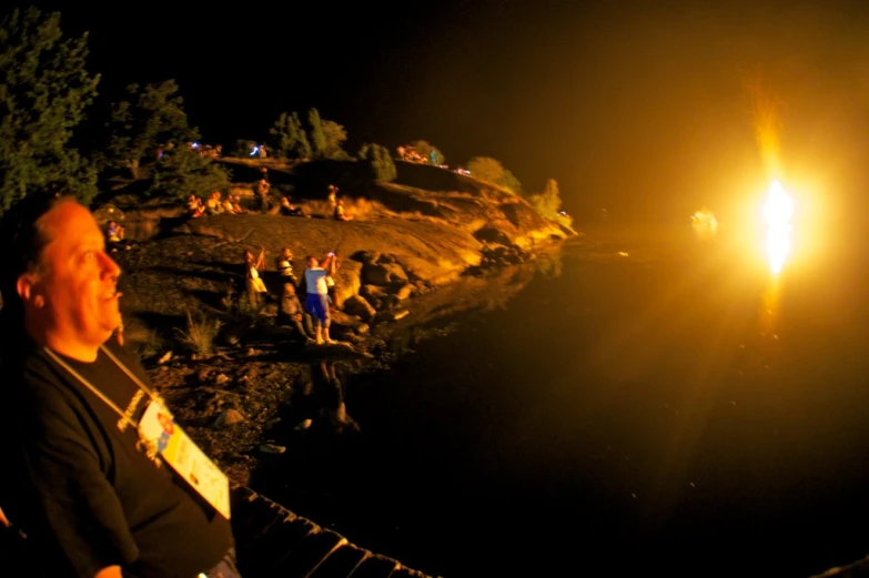 a man standing next to a fire burning on top of a hill