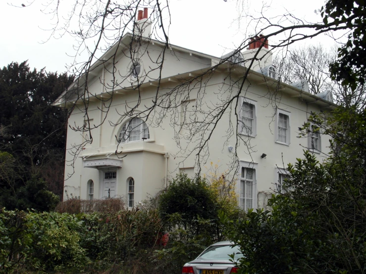 an old white house in the middle of the woods