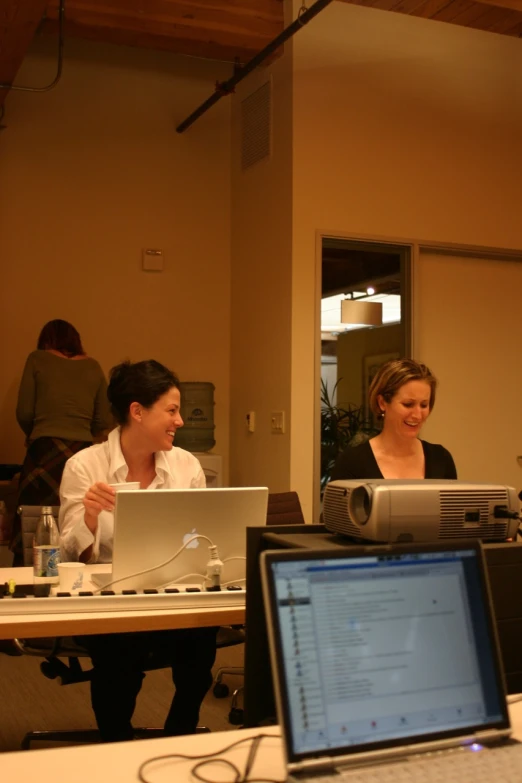 people in a meeting talking while on their laptop computers