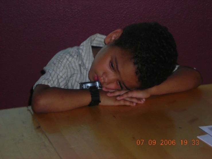 a small child leaning his head on a table
