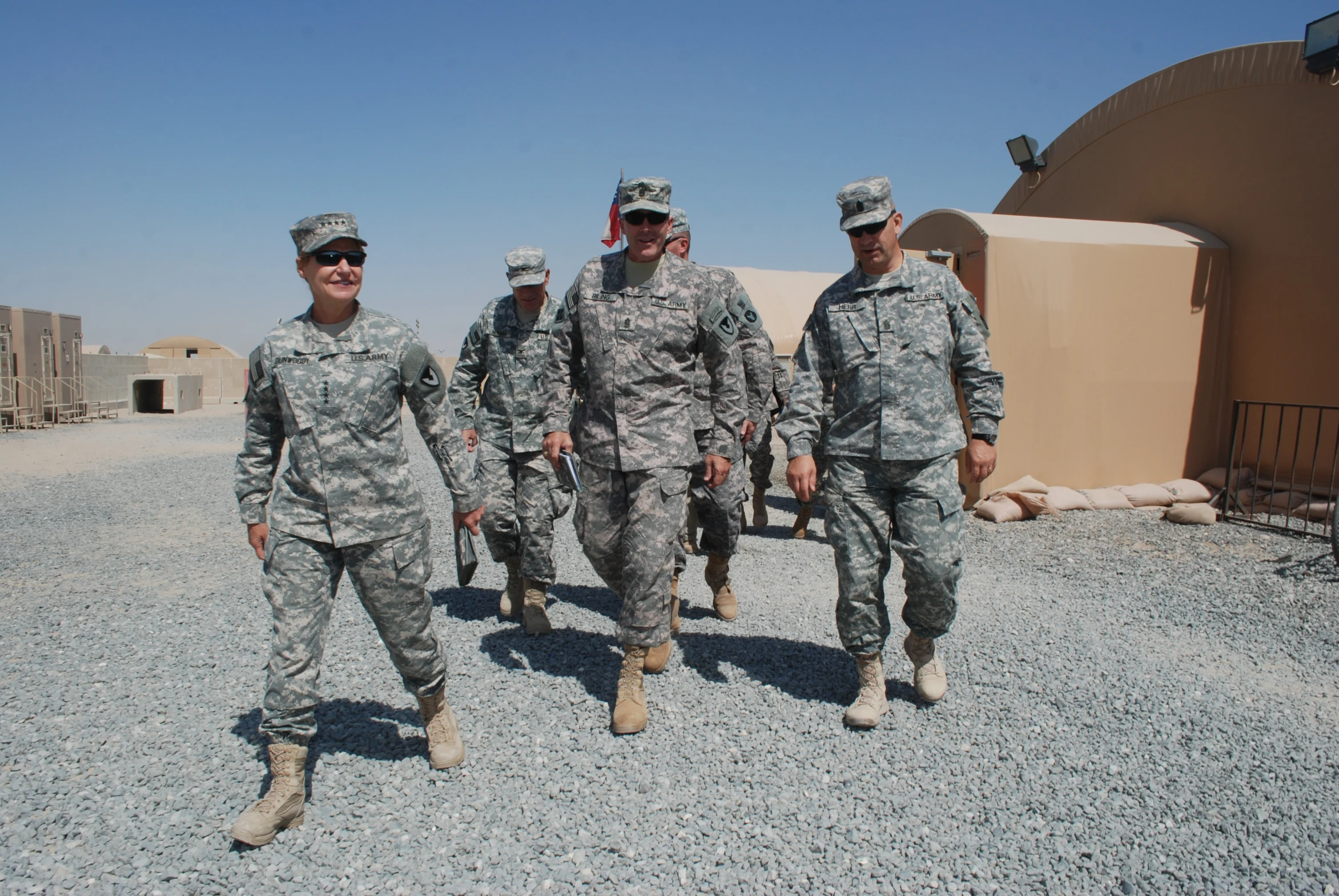 four men in uniforms walking across a gravel lot