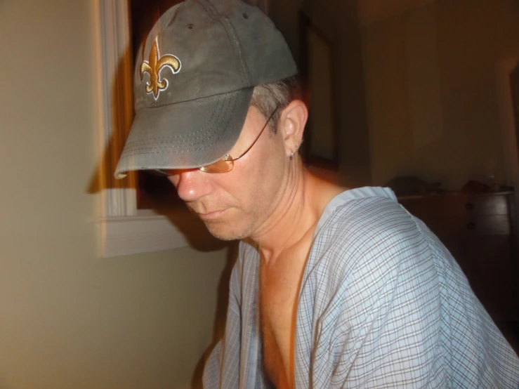 a man wearing glasses and a cap staring at his cell phone