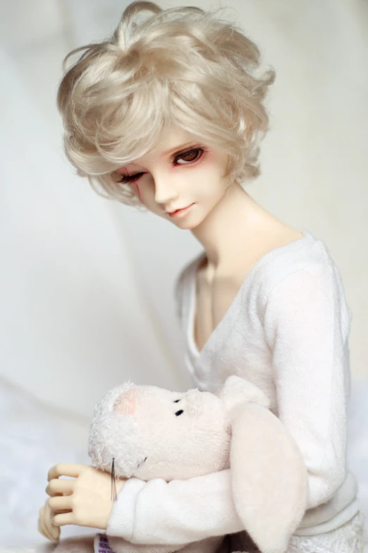a doll dressed in a white sweater holding a stuffed rabbit