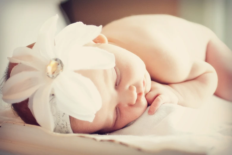 a newborn baby is wearing a white flower