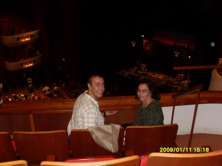 a woman sits with a man in a theater seat