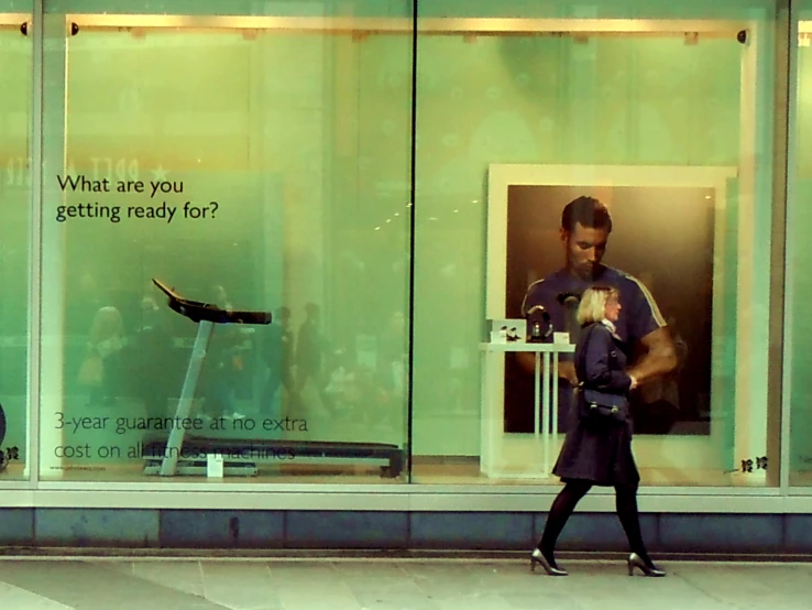 a woman walking by a window displaying a dressmaker in the window