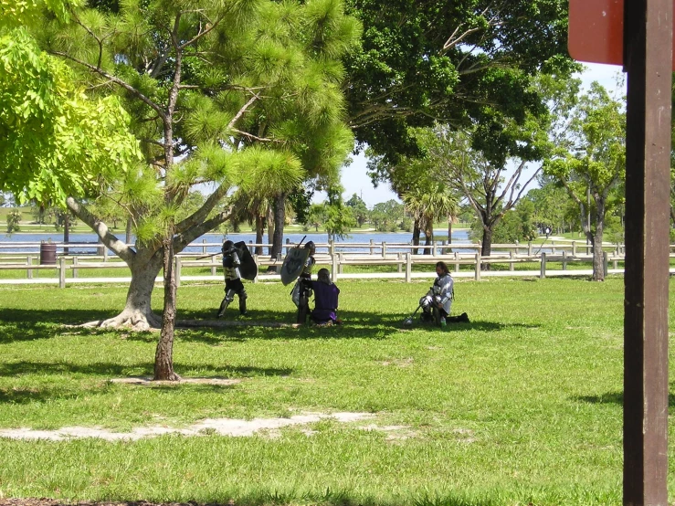 four people sitting in the grass by the water