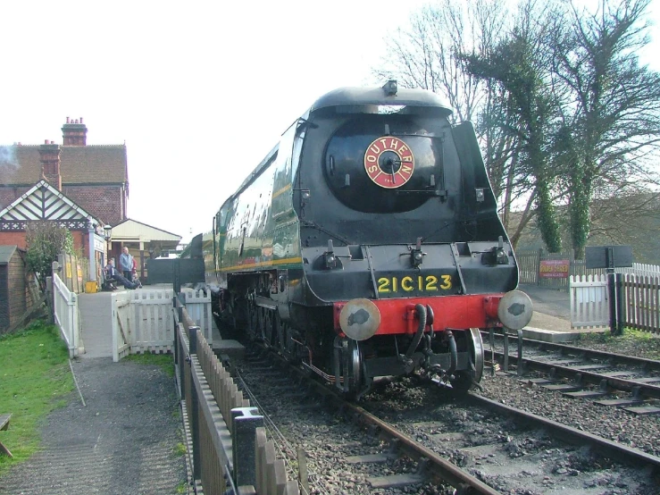 a steam locomotive traveling down train tracks near a fence