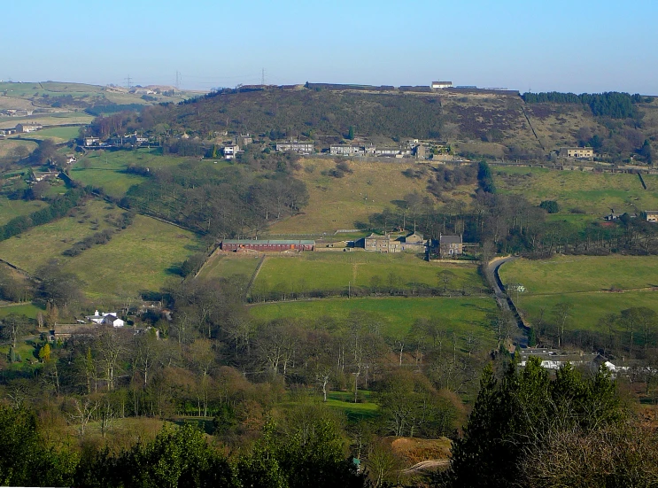 a green hilly area with small houses on a hill