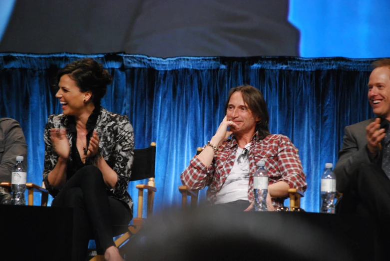 three people sitting next to each other on a stage