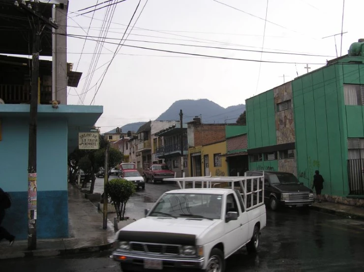 a white truck driving down a road past tall buildings