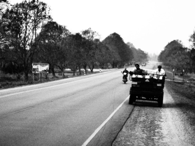 an open road with people riding in the back of it