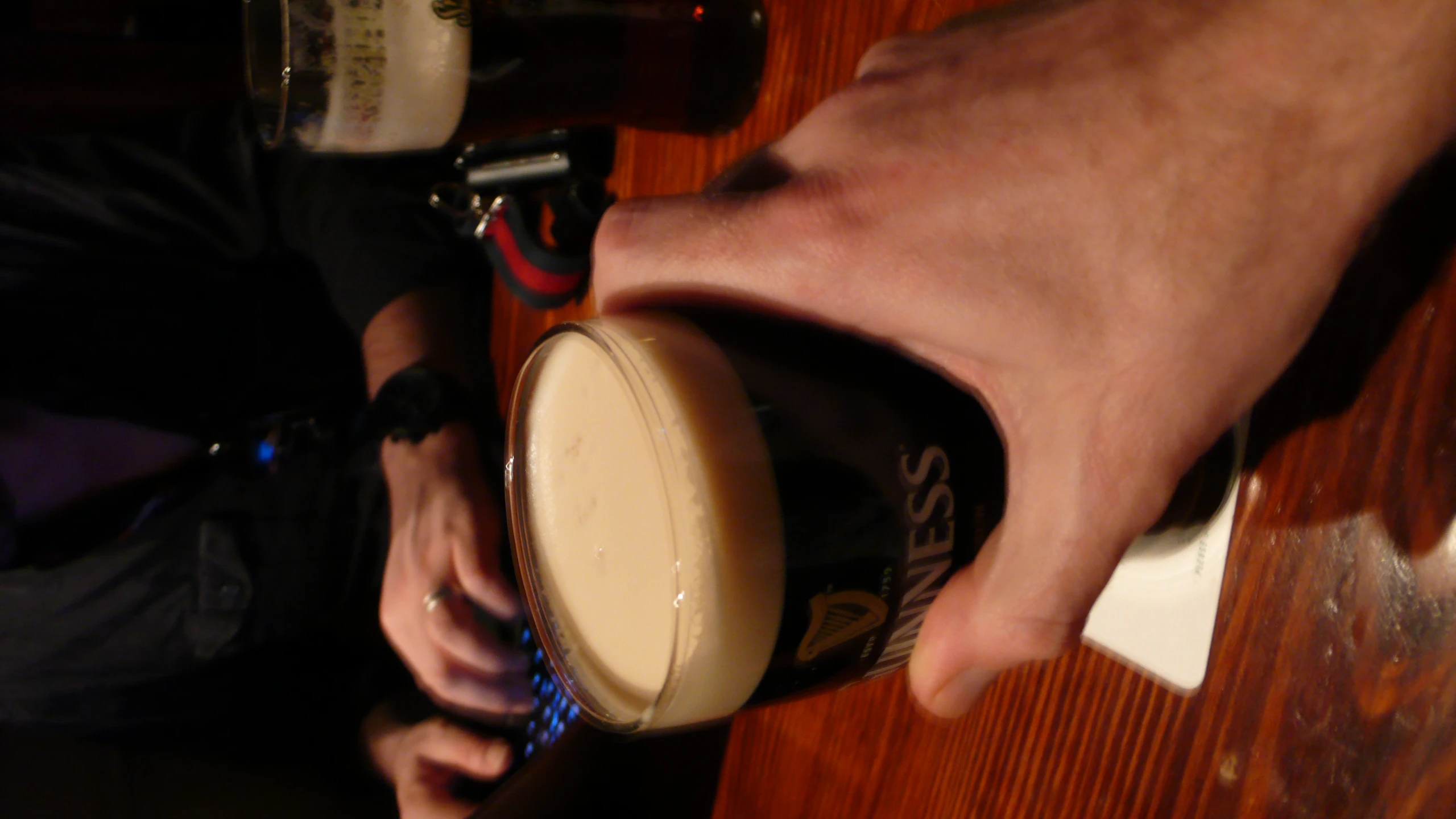 a hand holding a beer near two glasses