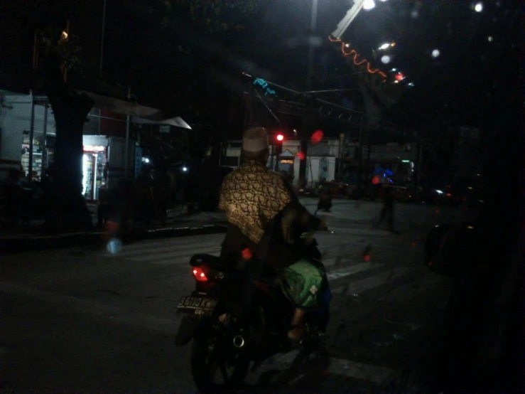 a man riding on the back of a motorcycle at night