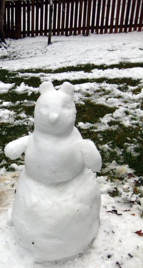 a snow man stands in the yard covered with snow