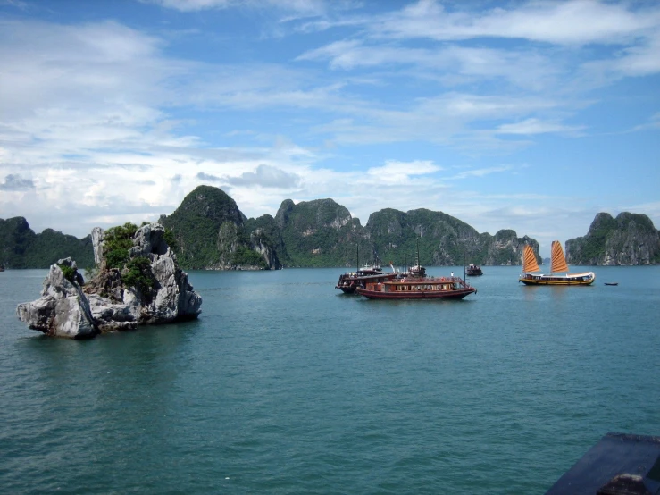 some boats and a large rock formation in the water