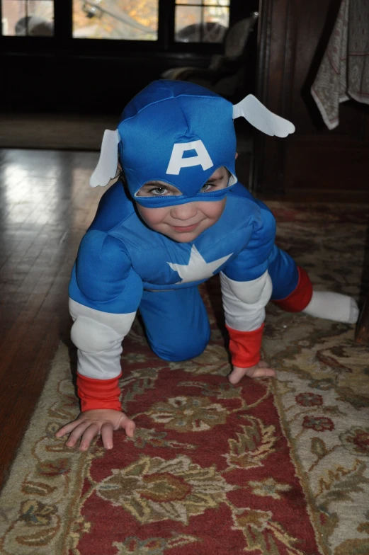 a baby dressed as captain america on the floor