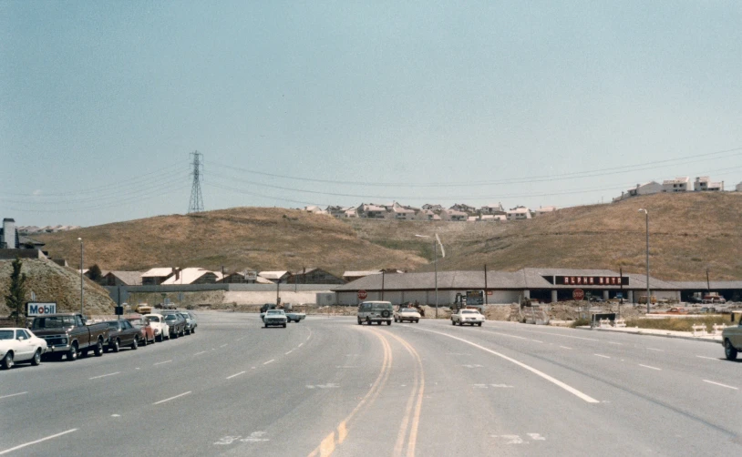 a view of several cars on a road, one driving down the side and two facing away from the camera