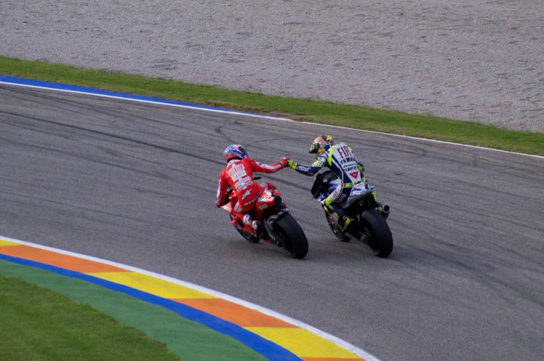 two motorcyclists touching hands on a track