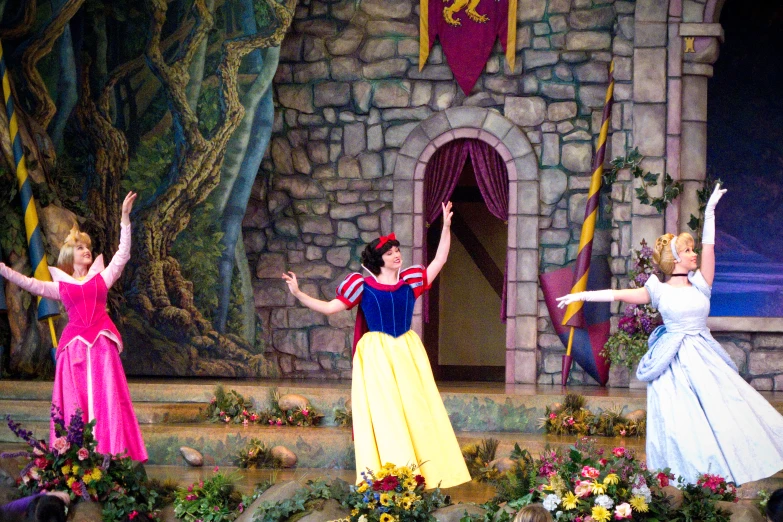 four princesses in costumes dance in front of a castle