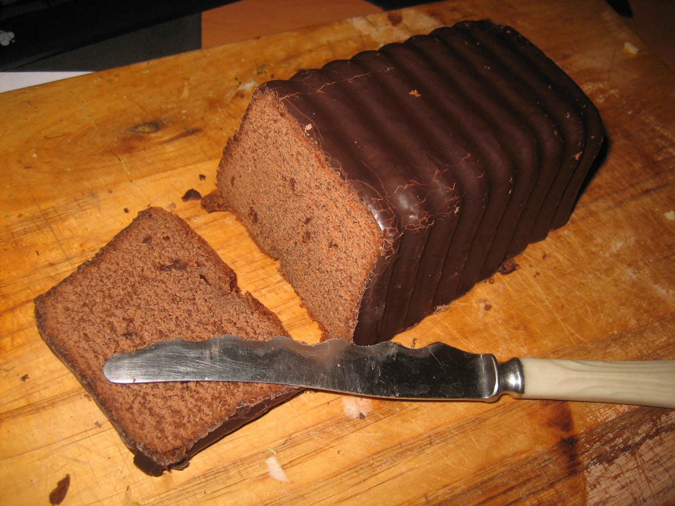 sliced loaf of chocolate cake with a knife on a  board