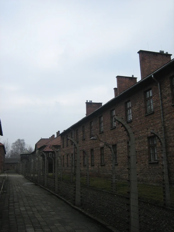 there is an old red brick building next to the fence