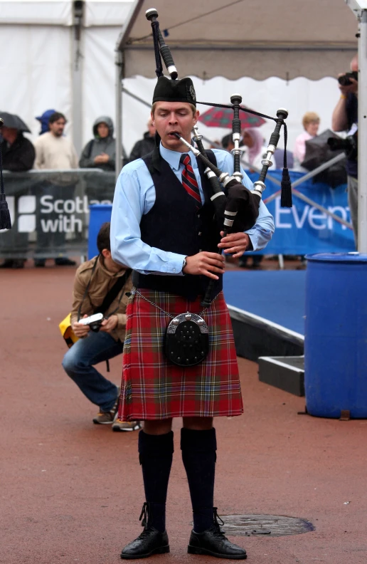 man in a kilt holding a bagpipe to his ear