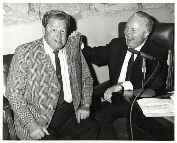 two men sitting down and talking into microphone