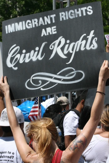 a group of people holding a sign that says immigrant rights are evil rights
