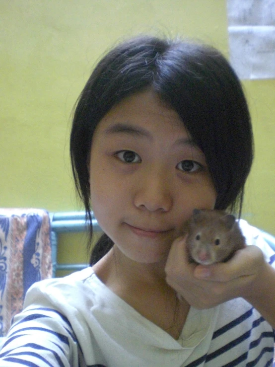 a girl in striped shirt holding a small animal