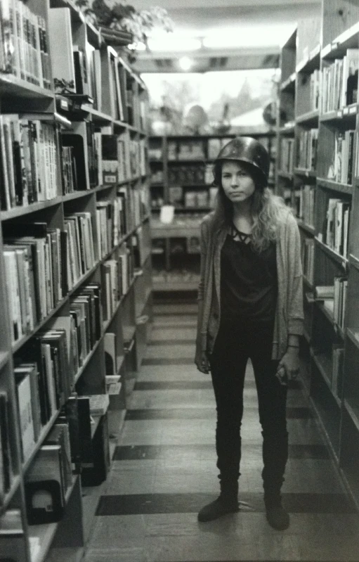 a man wearing a helmet standing between rows of books