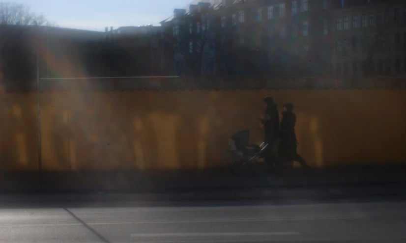 a couple of people that are walking next to a wall