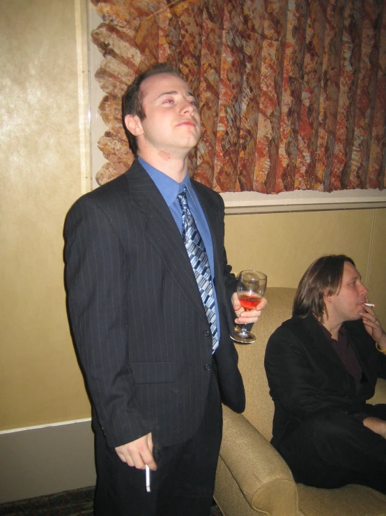 a man in a business suit holding a glass with his mouth open and looking up