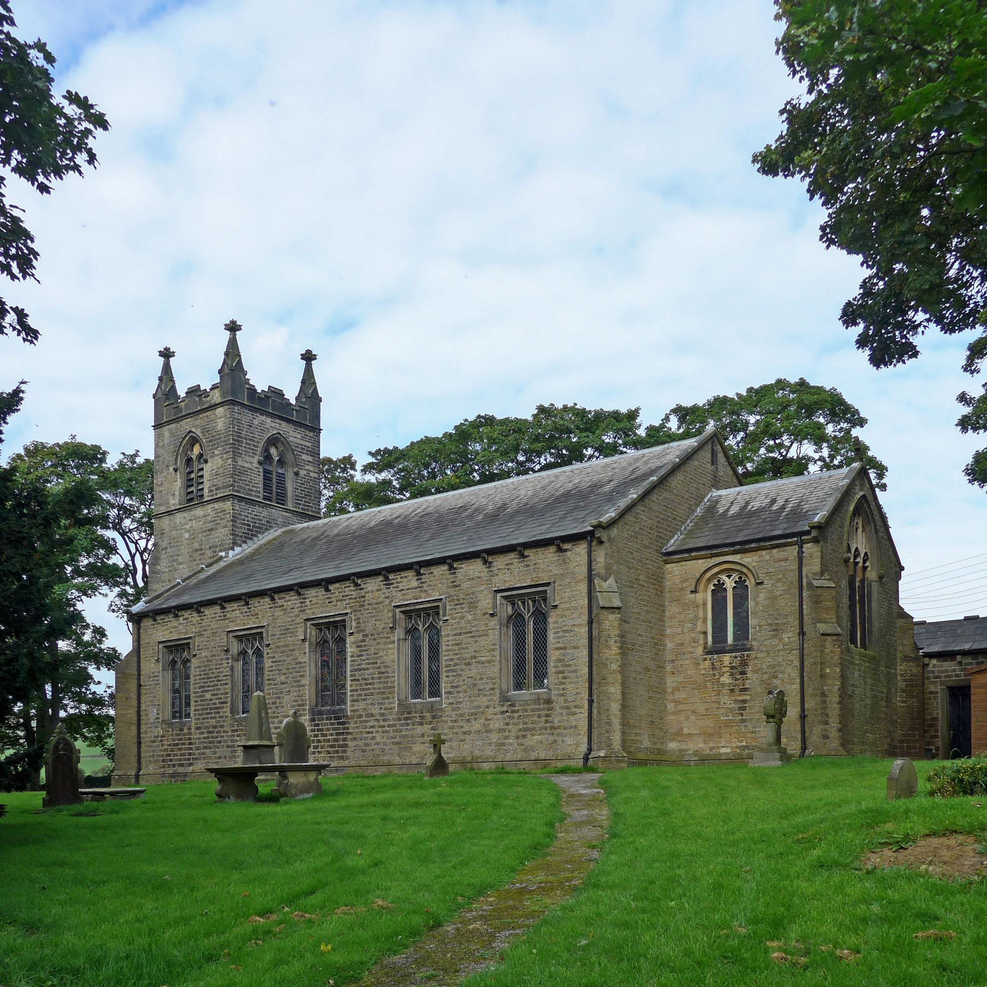 a po of a brick church building, with some grass and trees