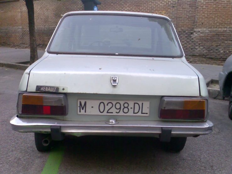 an old white car parked on the side of a street